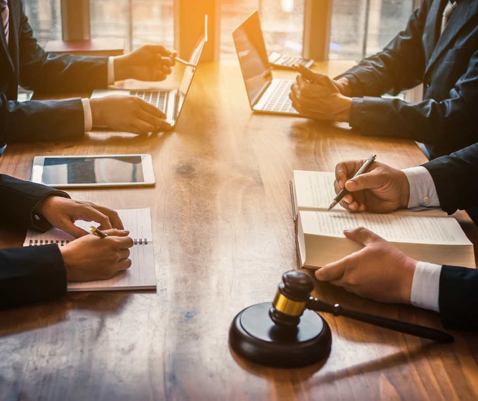 boardroom table with 4 professionals in suits and a gavel