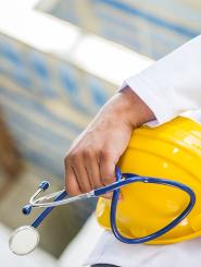 Doctor hand with stethoscope and yellow hard hat