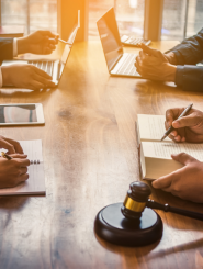 boardroom table with 4 professionals in suits and a gavel